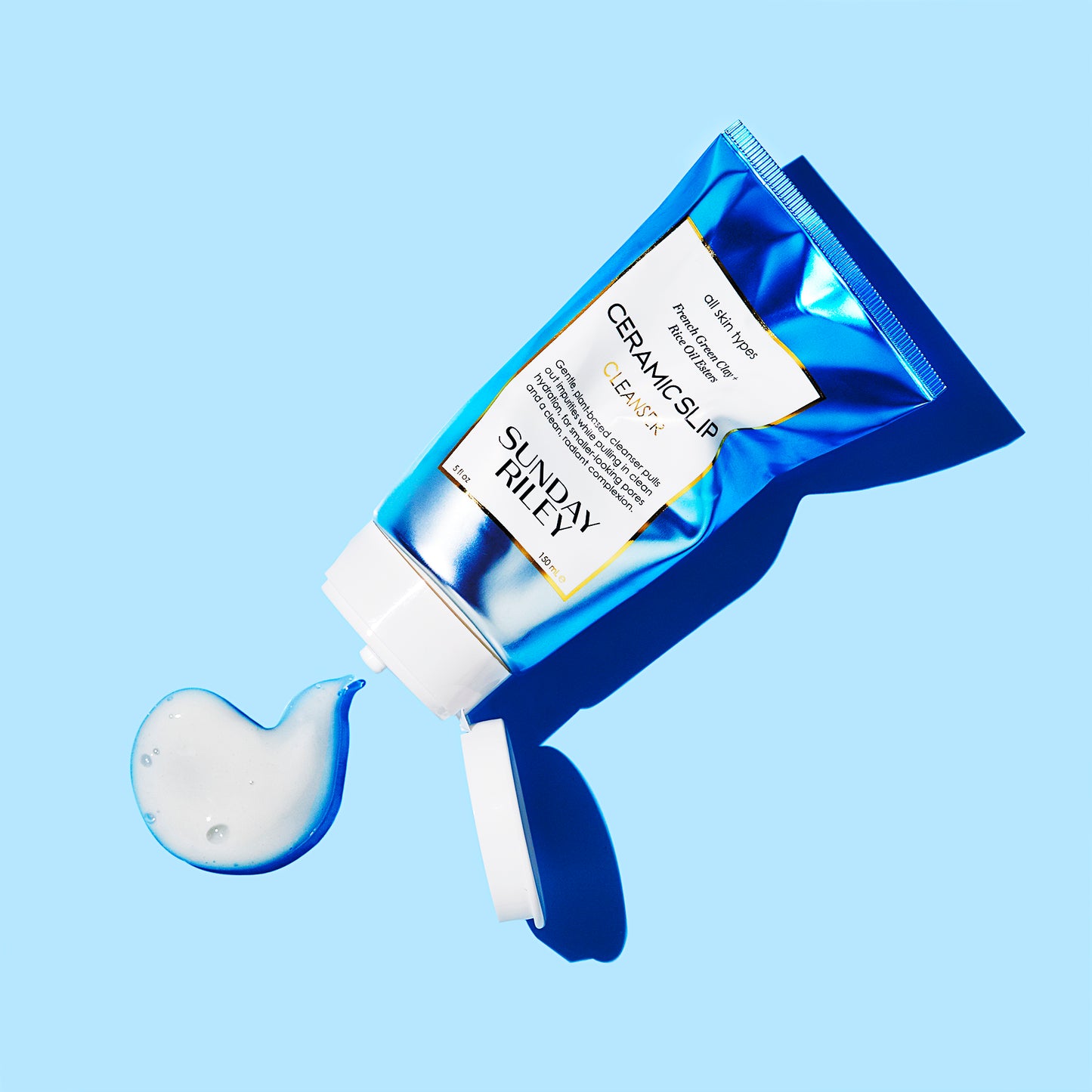 Light blue background, crushed Ceramic Slip tube, white goop spilling out