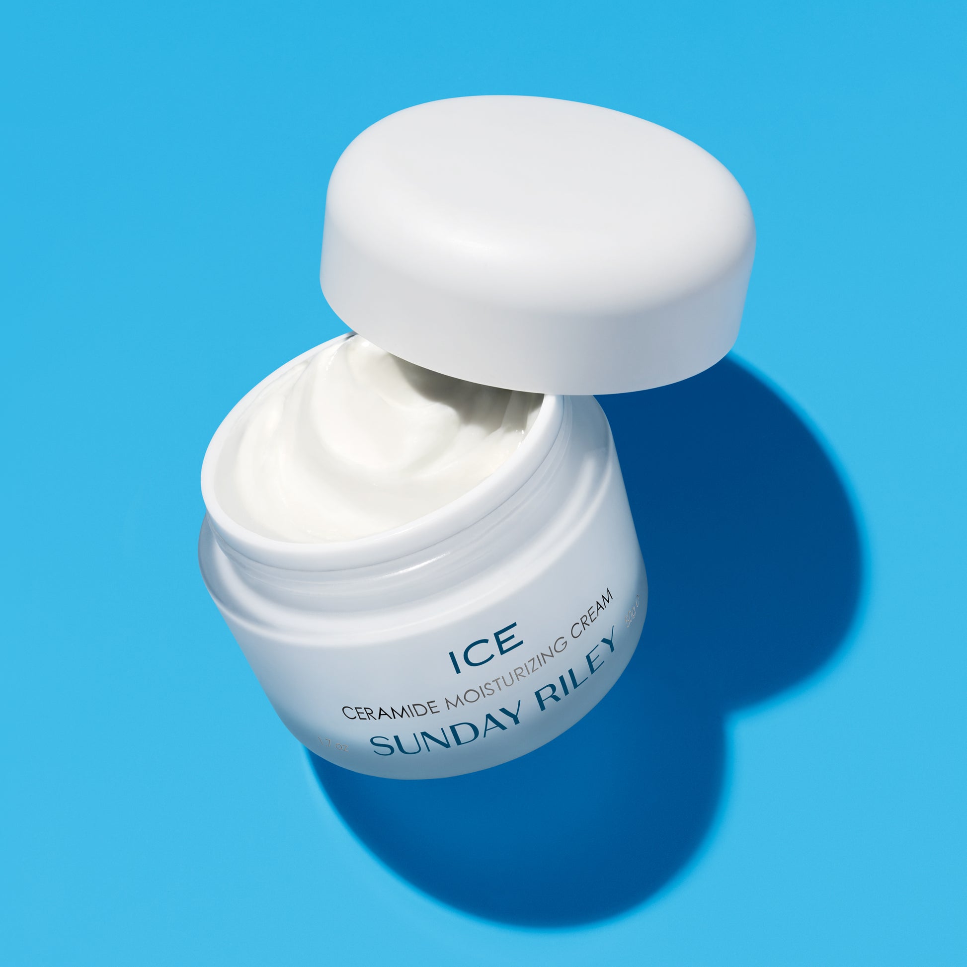 Ice Ceramide Moisturizing Cream, product with open lid against a blue background.