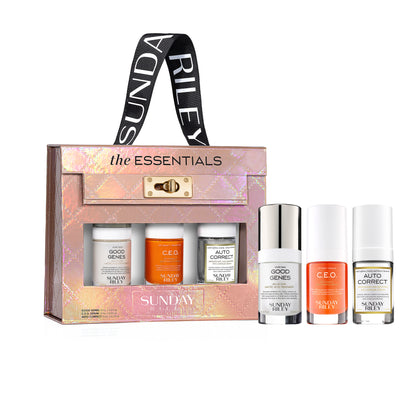Sunday Riley The Essentials gift set featuring a holographic pink and gold carrying case with a black branded strap, alongside four skincare and beauty bottles displayed in front on a white background.