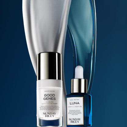 Dark blue background, Good Genes with a white goop falling behing the bottle and Luna Sleeping Night Oil with a blue oil falling behind the bottle