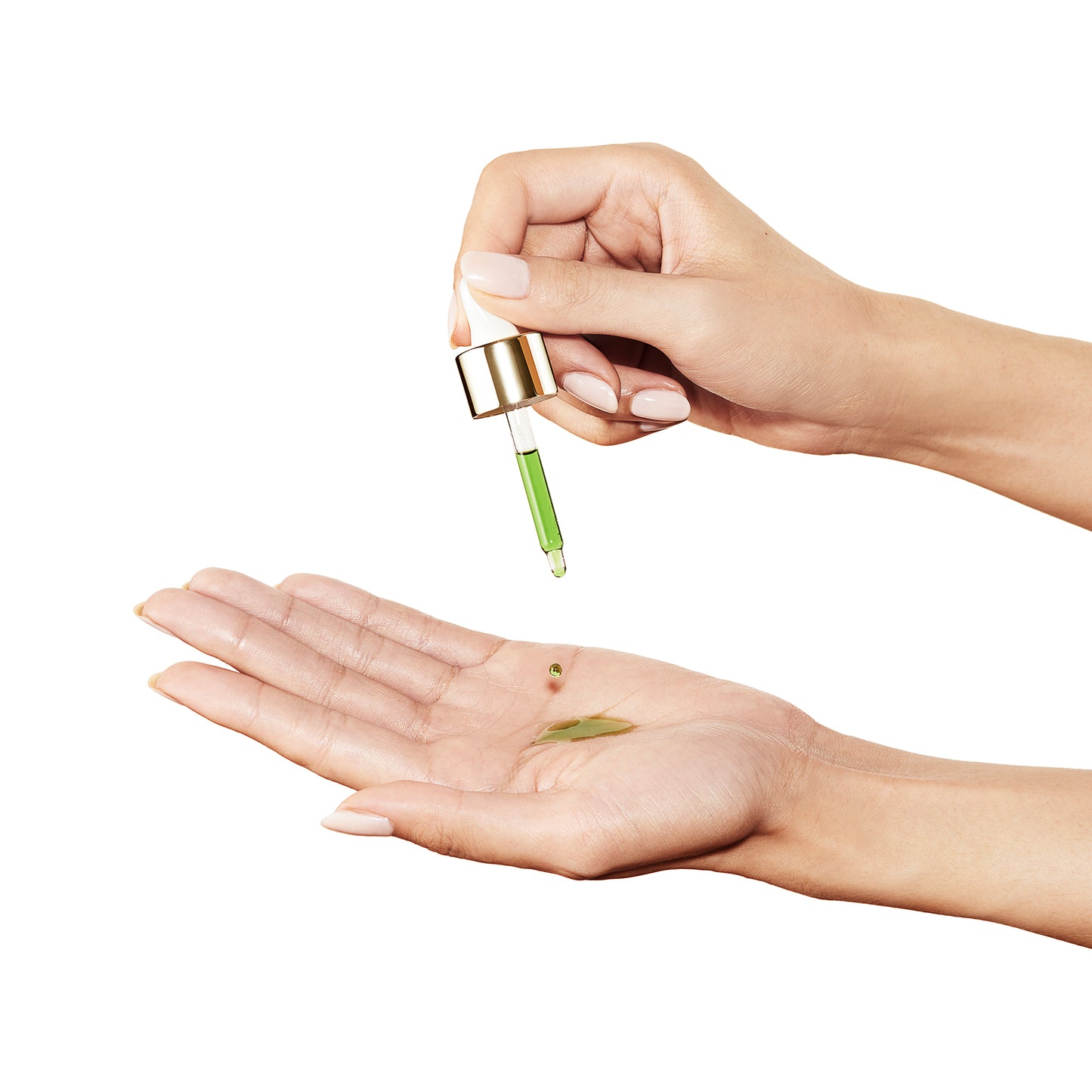 Hand holding dropper, dispensing green UFO face oil onto palm, light pink manicure